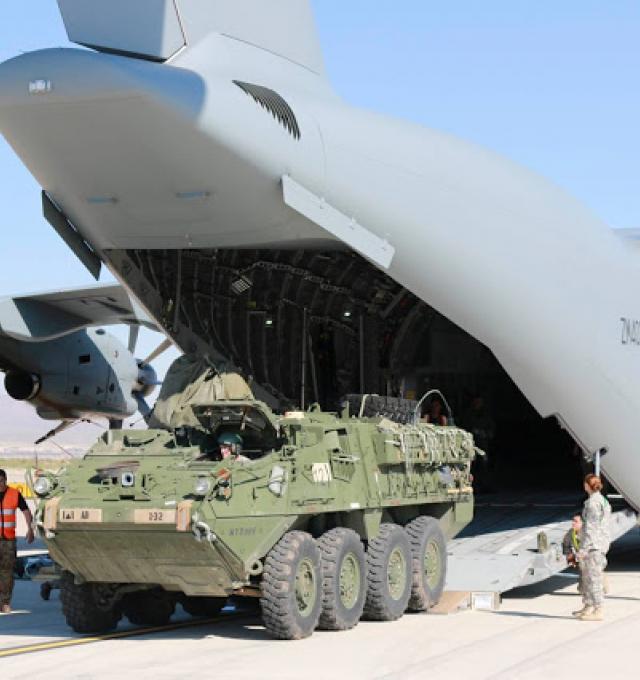 Een pantservoertuig rijdt uit een cargovliegtuig op een militaire landingsbaan