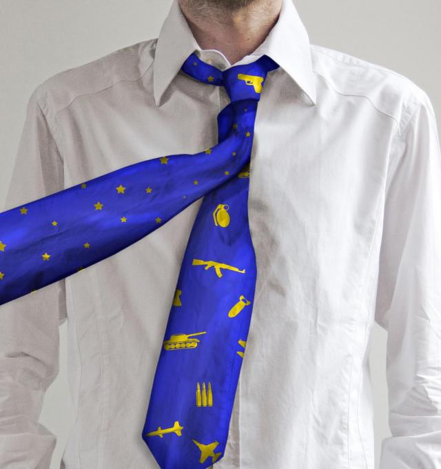 een man draagt een stropdas met europese sterren, met daaronder een tweede stropdas met wapens.
